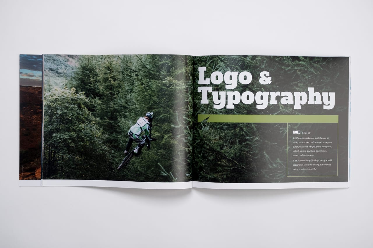 A custom magazine laying open and printed with Logo & Typography in white and a person riding a motocross bike.