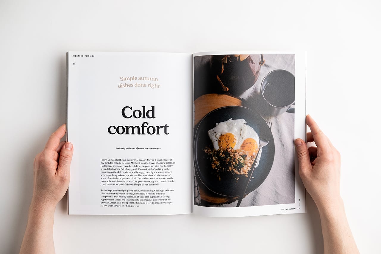 Two hands holding open a custom magazine printed with Cold Comfort and an image of eggs on a plate.