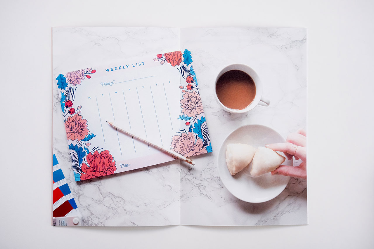 A custom lookbook laying open to images of stationery, a cup of tea and a plate of cookies.