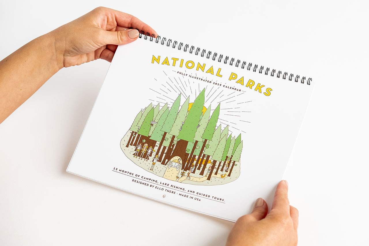 Two hands holding a custom calendar printed with a wire binding and an illustration of a national park on the cover.