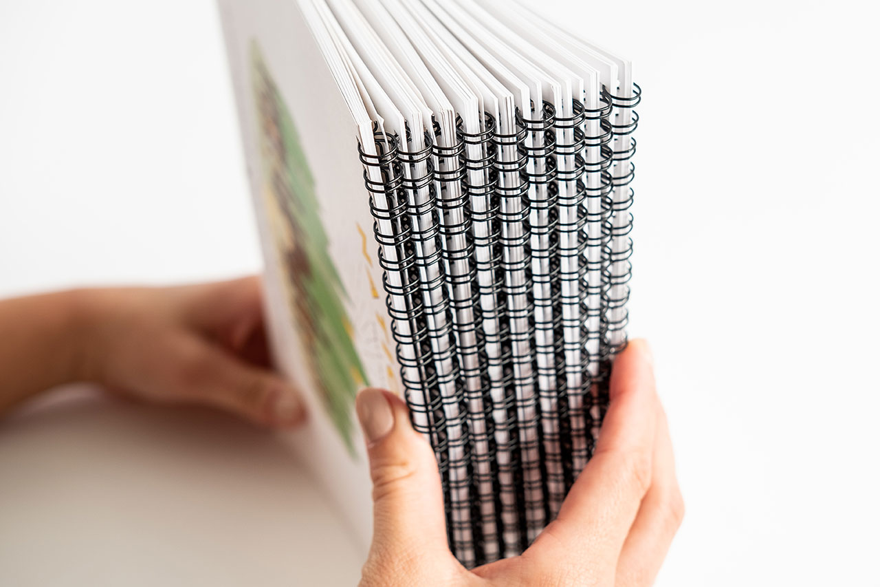 Two hands holding a stack of wire bound calendars with national parks illustrations on the cover.