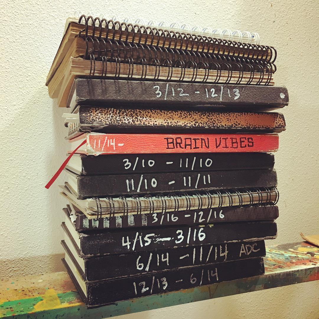 A stack of used notebooks with spiral bindings and perfect bindings.