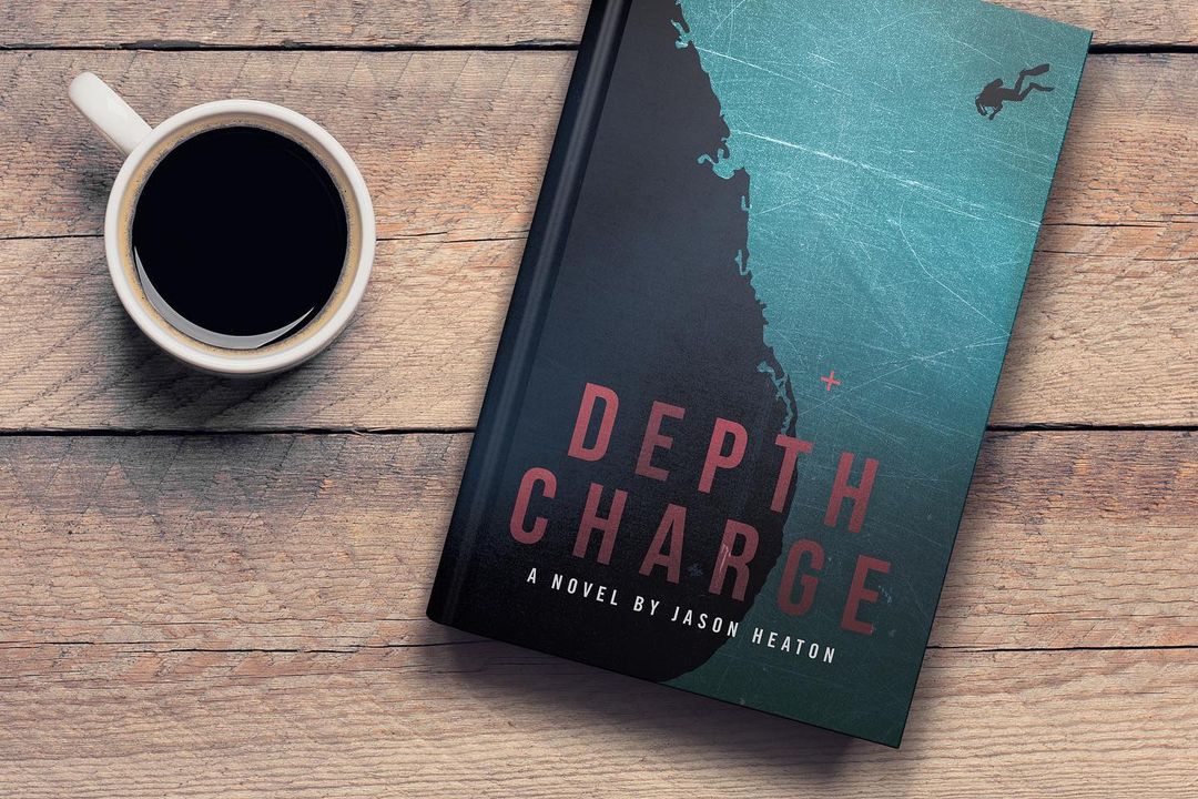 A book called Depth Charge next to a cup of coffee on a wooden table.