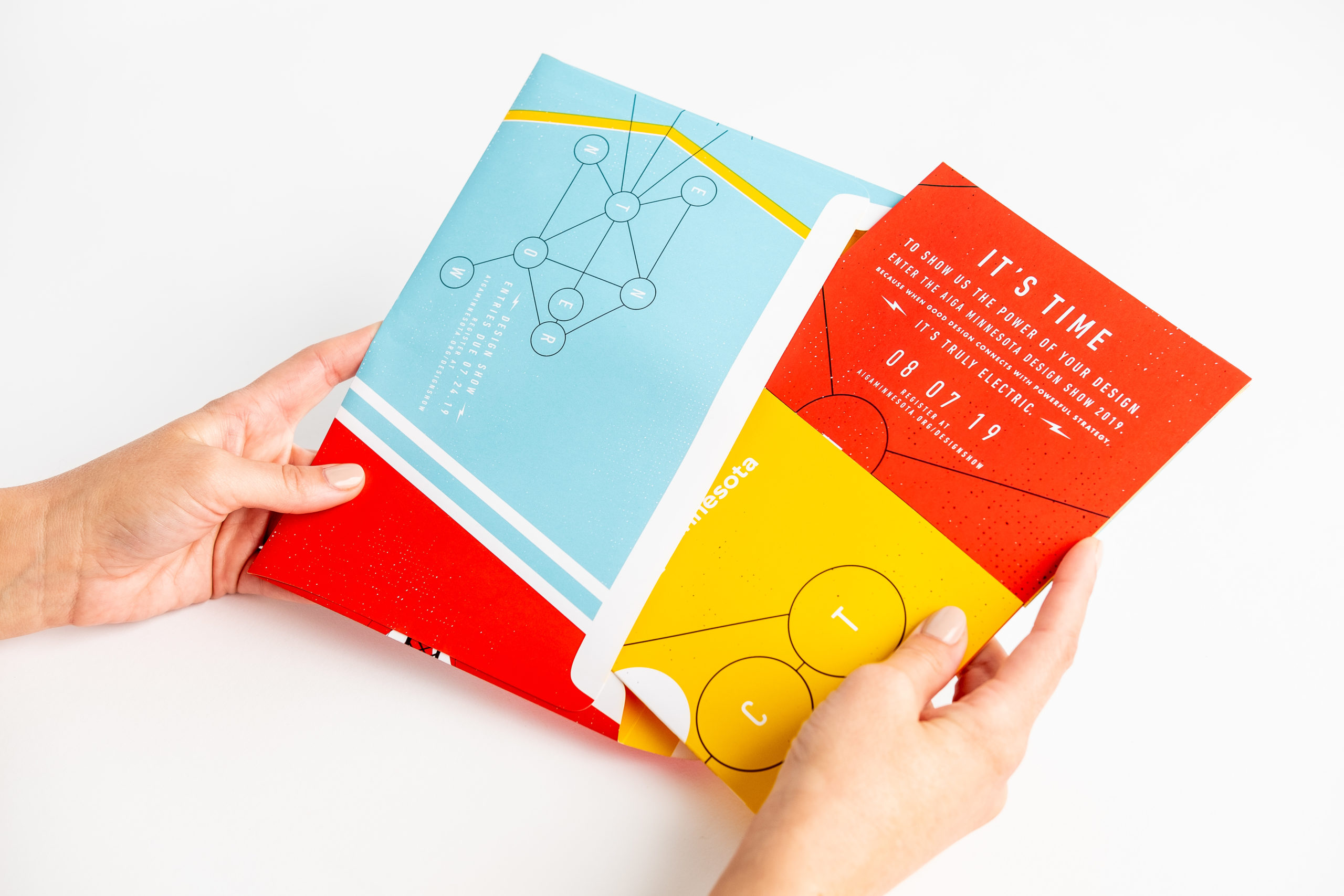 Two hands putting a brochure into a matching direct mail envelope.