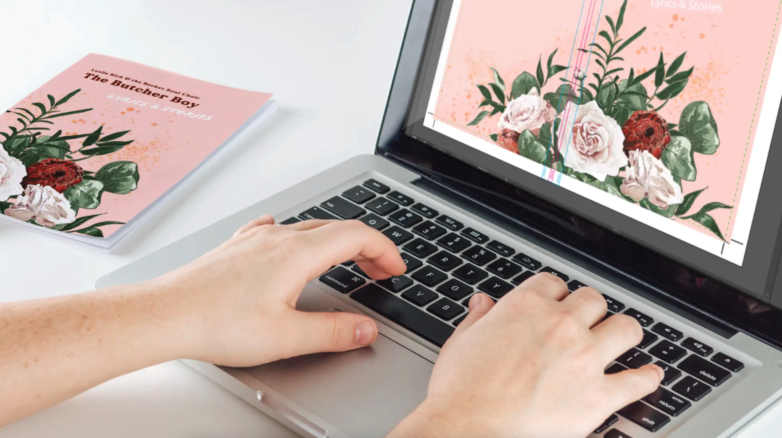 Two hands typing on a laptop with a soft print proof on the screen.