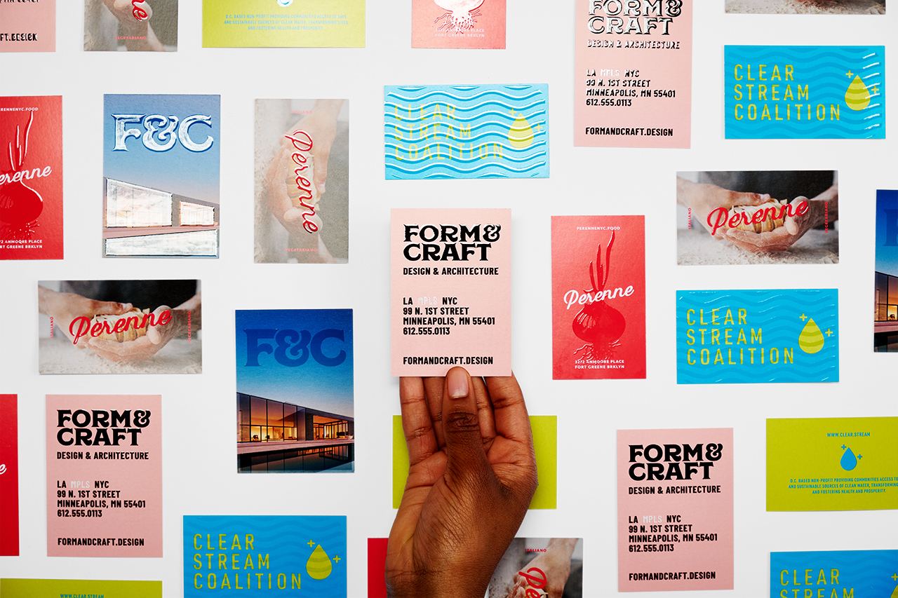 A hand holding a custom business card printed with raised UV ink with more cards around it.