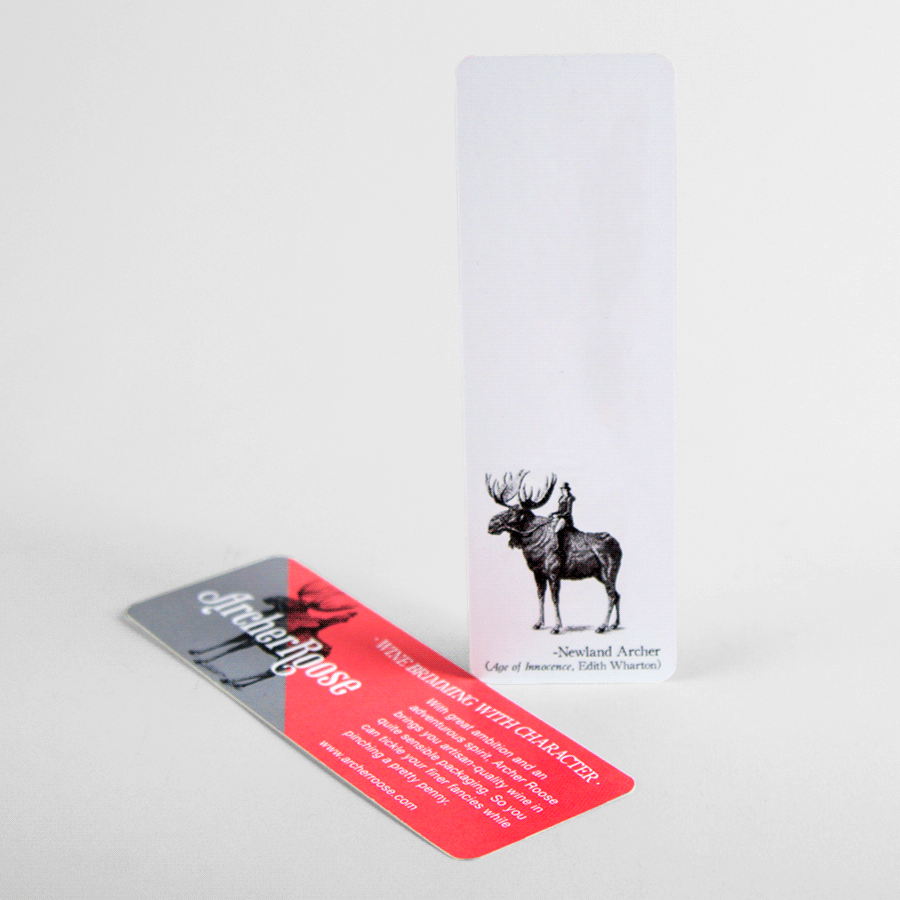 A pink and gray bookmark laying next to a standing white bookmark with a moose illustration.